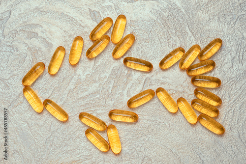 Omega3 capsules in fish shape silhouette on a cement background. EPA and DHA are essential fatty substances that our bodies need on a daily basis.