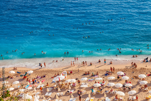 Fototapeta Naklejka Na Ścianę i Meble -  People Crowd Relaxing On Beach. Swimming people in sea. Top view of Kaputas Beach between Kas and Kalkan. The best beach in Turkey with turquoise waters, Mediterranean Sea
