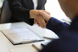 Businessmen shake hands while negotiating employment agreements after interviews.