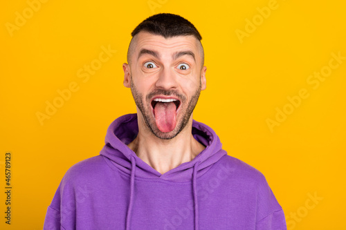 Photo portrait young man wearing violet pullover fooling showing tongue isolated bright yellow color background