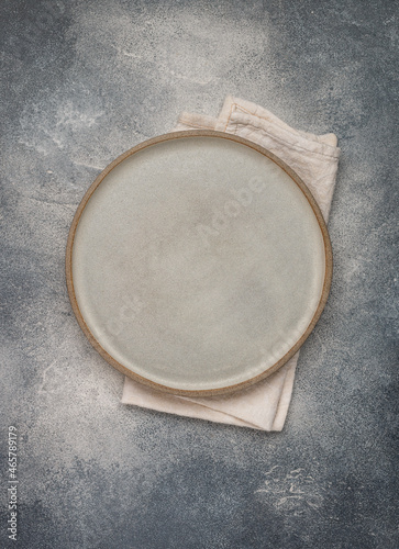 empty grey plate and linen napkin on grey concrete or stone table. Cooking background. Rustic style. Selective focus. Top view, copy space