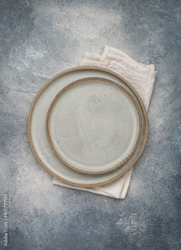 empty grey plates and linen napkin on grey concrete or stone table. Cooking background. Rustic style. Selective focus. Top view, copy space