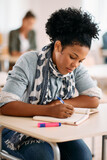 African American female student takes notes during class at the university.