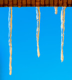 Icicles in winter against a blue sky.