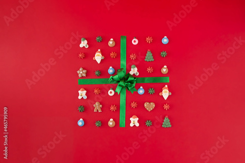 Gift box of cookies with green ribbon on the red background. Christmas holiday creative concept.