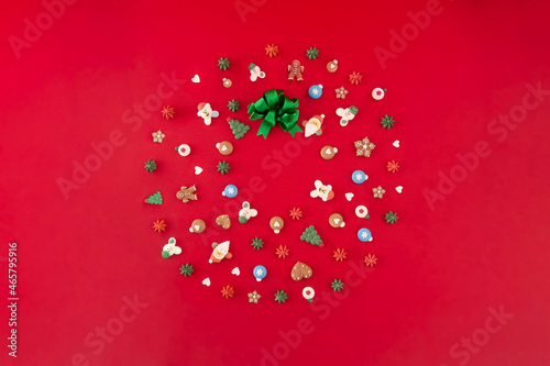 Christmas wreath of cookies with green ribbon on the red background. Christmas holiday creative concept.