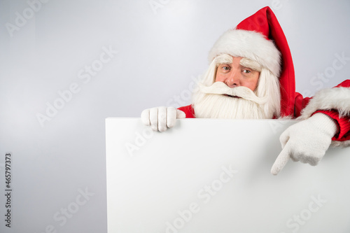 Santa Claus points to an empty white space. Promotional offer for Christmas.