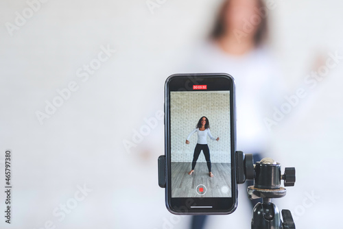 Young black woman created her dancing video content by smartphone camera to live streaming to social media application for view, like and share. stay at home to protect spread of coronavirus covid-19.