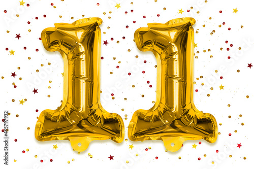The number of the balloon made of golden foil, the number eleven on a white background with multicolored sequins. Birthday greeting card with inscription 11. Numerical digit, Celebration event. photo