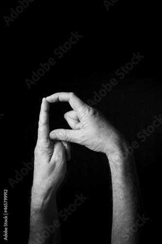 B+W image of hand demonstrating BSL sign language letter D isolated against black background