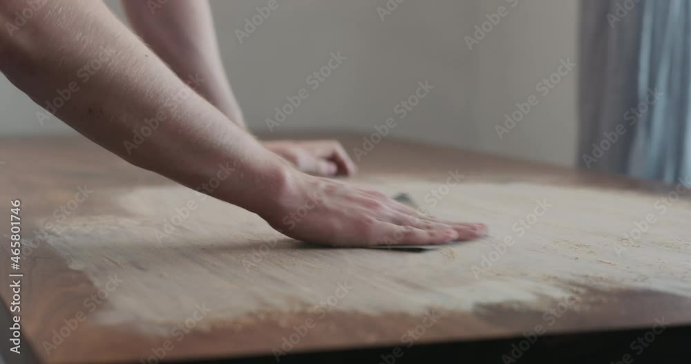 Slow motion slide orbit shot of man hand sanding black walnut wood table Slow motion slide orbit shot of man hand sanding black walnut wood table