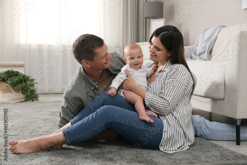 Happy family with their cute baby on floor in living room
