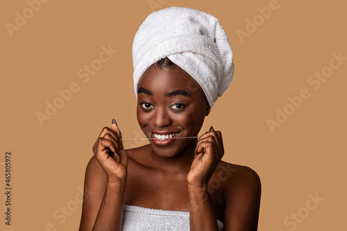 Young black woman using dental floss looking at camera