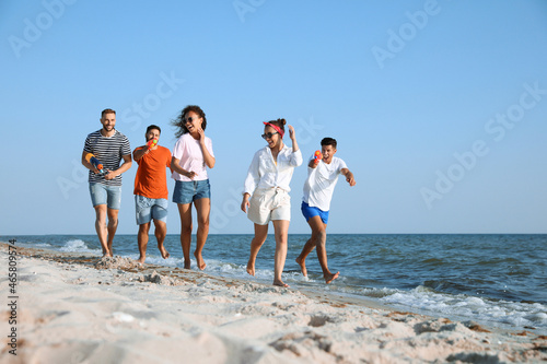 Group of friends with water guns having fun on beach photo