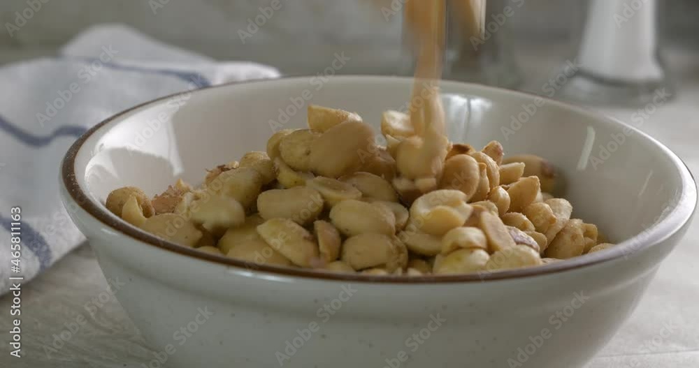 Pouring roasted salted peanuts into a bowl close up Pouring roasted salted peanuts into a bowl close up