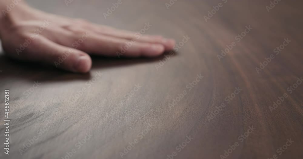 Slow motion of man hand checking toned walnut table surface with oil finish