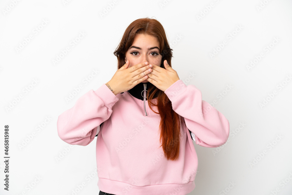 Young redhead woman isolated on white background covering mouth with hands Young redhead woman isolated on white background covering mouth with hands