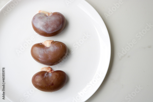 Three Kidneys of a goat on a white plate with copy space.
