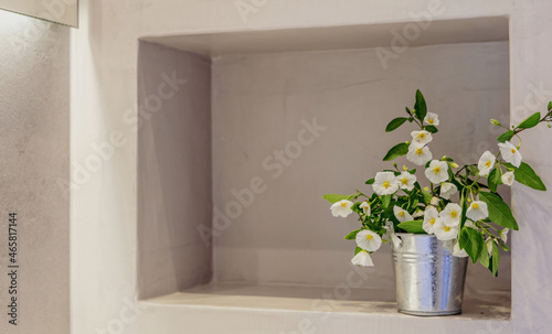 White flowers plant in a metal pot on a wall shelf, empty space, room interior template