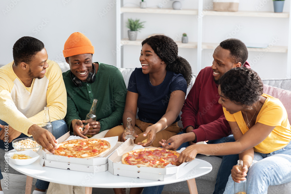 Cheerful african american friends having home party, eating pizza