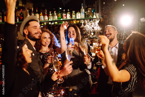 Group of friends partying in a nightclub and toasting drinks with champagne. Happy people enjoying winter holiday. Party, celebration, drink, birthday concept.