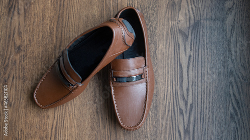 BROWN MOCCASIN SHOES, ON WOODEN FLOOR WITH NATURAL LIGHTING AND SPACE FOR TEXT