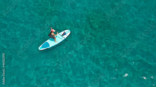 Aerial drone photo of young woman practising paddle board or sup in tropical Caribbean sapphire crystal clear calm waters © aerial-drone