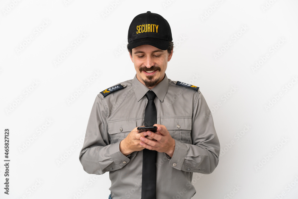 Young caucasian security man isolated on white background sending a message with the mobile Young caucasian security man isolated on white background sending a message with the mobile