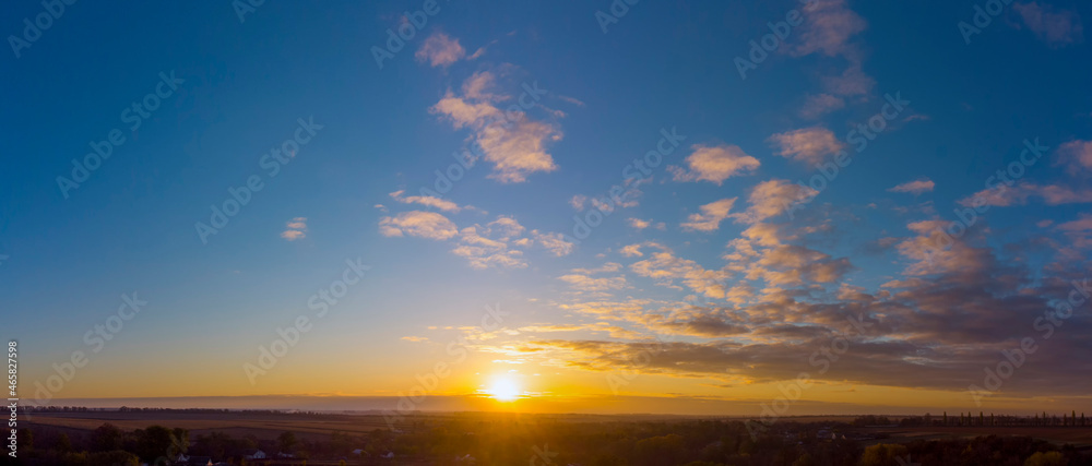 Panorama of sunrise. Blue sky with orange clouds.