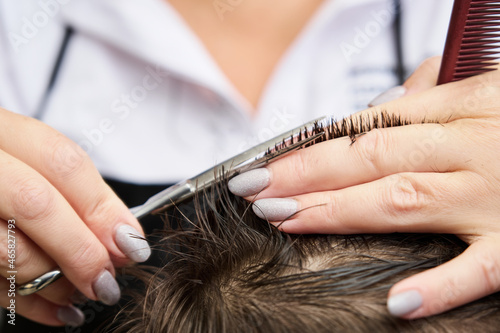 woman hairdresser cuts a little boy's hair