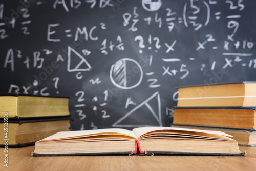 School books on desk infront of blackboard with formulas. education concept