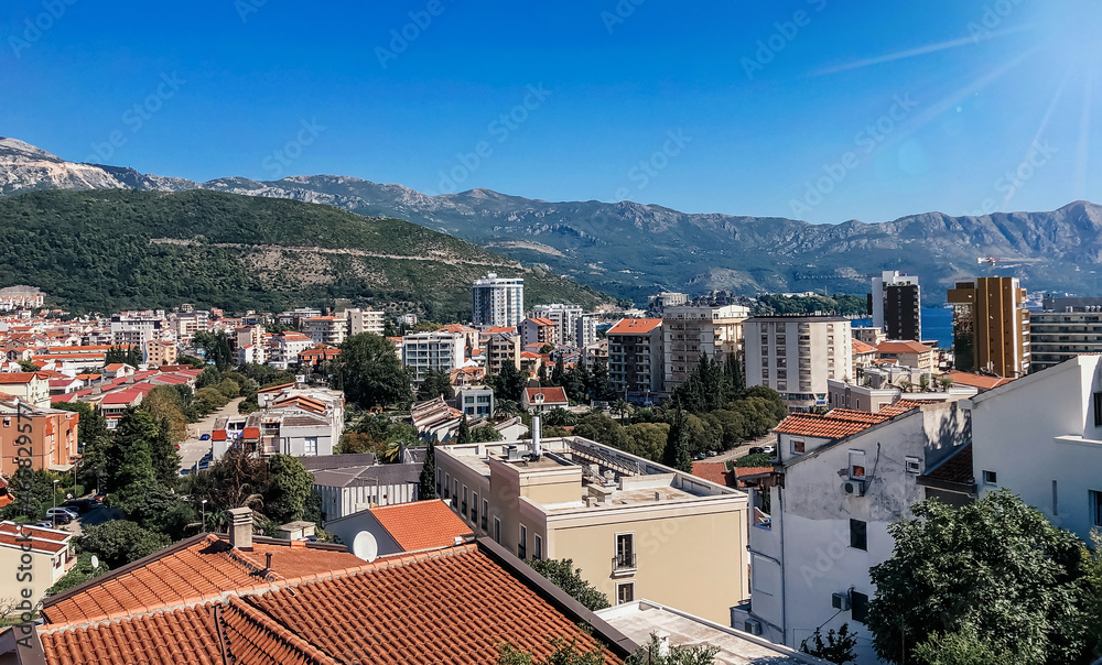 Bright traditional red and orange tiled roofs of houses against the backdrop of beautiful mountains in Montenegro