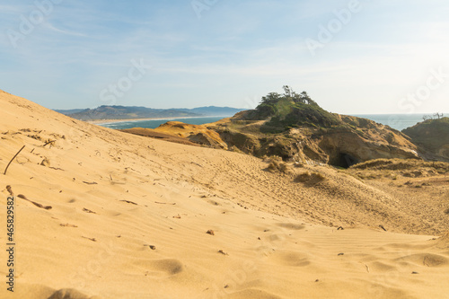 Deserted ocean shore. Yellow sandy hills, the ocean can be seen in the distance. Blue sky. Calm scenes. Privacy, rest, relaxation, tourism, travel. Postcard, banner.