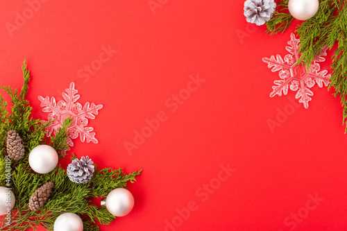 Christmas frame on a red background for your lettering. A beautiful composition - coniferous branches, Christmas balls, openwork snowflakes. New Year, Christmas, postcard, invitation.