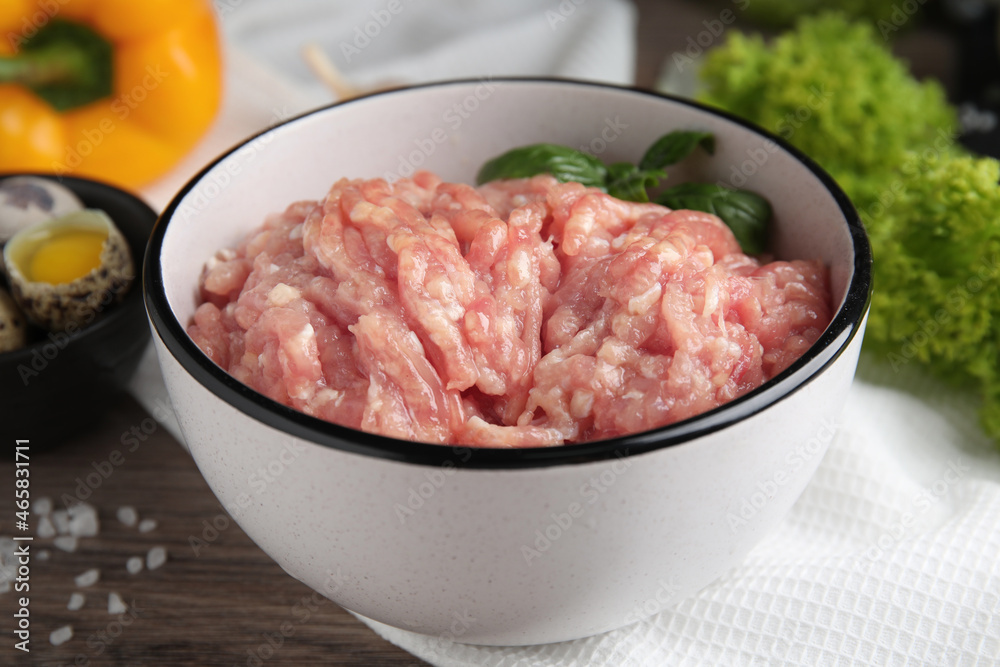 Raw chicken minced meat with basil on wooden table, closeup Raw chicken minced meat with basil on wooden table, closeup
