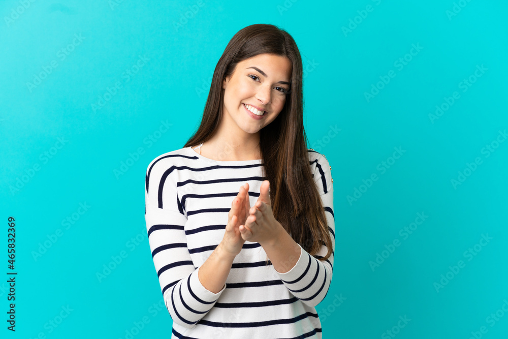 Fototapeta premium Teenager Brazilian girl over isolated blue background applauding after presentation in a conference