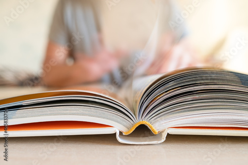 Close-up view of open book lying on table and man sitting in blurred background © salita2010