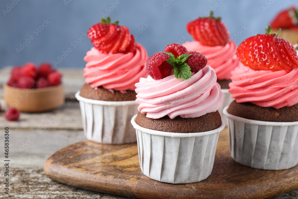 Sweet cupcakes with fresh berries on wooden table, closeup