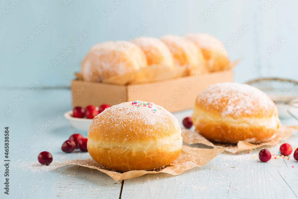 Jewish holiday Hanukkah concept - Hanukkah food doughnuts with powdered sugar and fruit jam on blue wooden background.