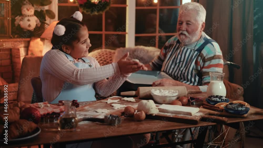 Cute little girl helps her disabled grandfather to prepare cakes for Christmas and New Year