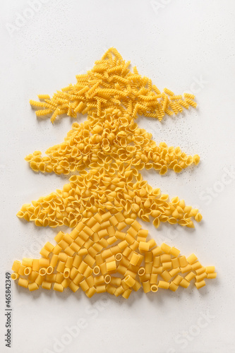 Alternative Christmas tree of dry Italian pasta on white background. Xmas vertical card. View from above. Food holiday concept.