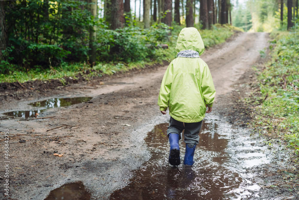 Child, toddler in blue rubber boots exploring muddy puddle. Family leisure in autumn forest. Lifestyle concept. Child, toddler in blue rubber boots exploring muddy puddle. Family leisure in autumn forest. Lifestyle concept.