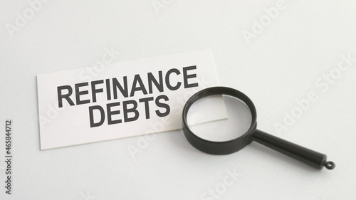 refinance debts word on paper and magnifying lens