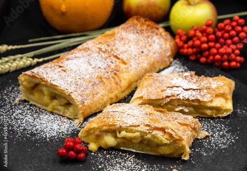 Strudel with apples. A wonderful dessert made of puff pastry. Black background.