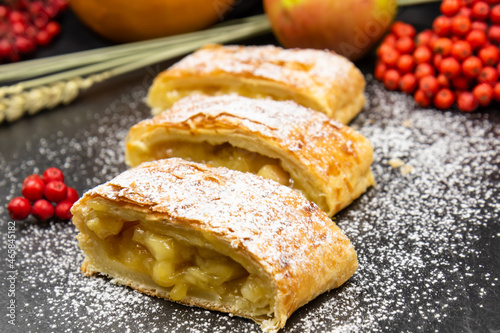 Strudel with apples. A wonderful dessert made of puff pastry. Black background.