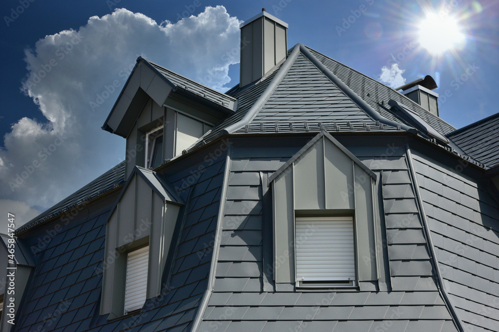 Saniertes Dach mit Stehfalz-Metall verblendeter Gaube und Aluminium-Schindel-Eindeckung auf einem Wohnhaus