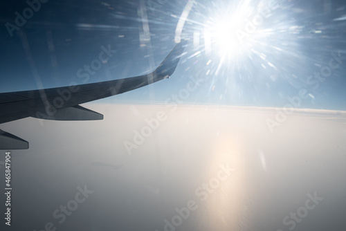 View from the window of a flying plane. Clouds, blue sky and a fragment of the airplane wing. photo
