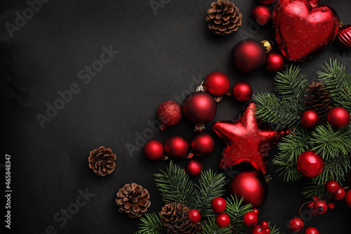 christmas tree branches background. fir tree branches, red ornaments and pine cones on black background