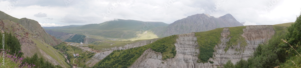 Fototapeta premium panorama of the Caucasus mountains in summer. beautiful shadows from clouds on the ground and rocks. picturesque plains, stones and nature