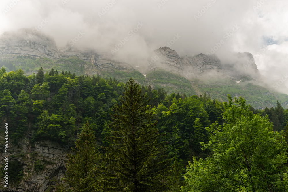 Appenzell, Switzerland, June 13, 2021 Mountain peaks in clouds and green trees